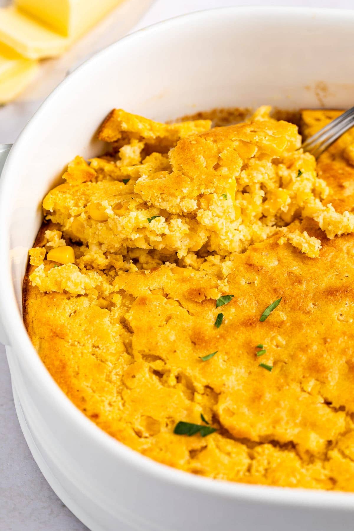 An oval casserole dish holding cornbread casserole.