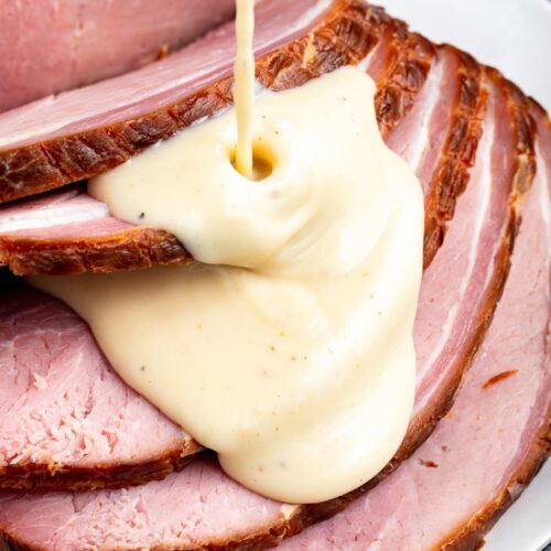 Sliced ham with ham gravy being poured over the top.