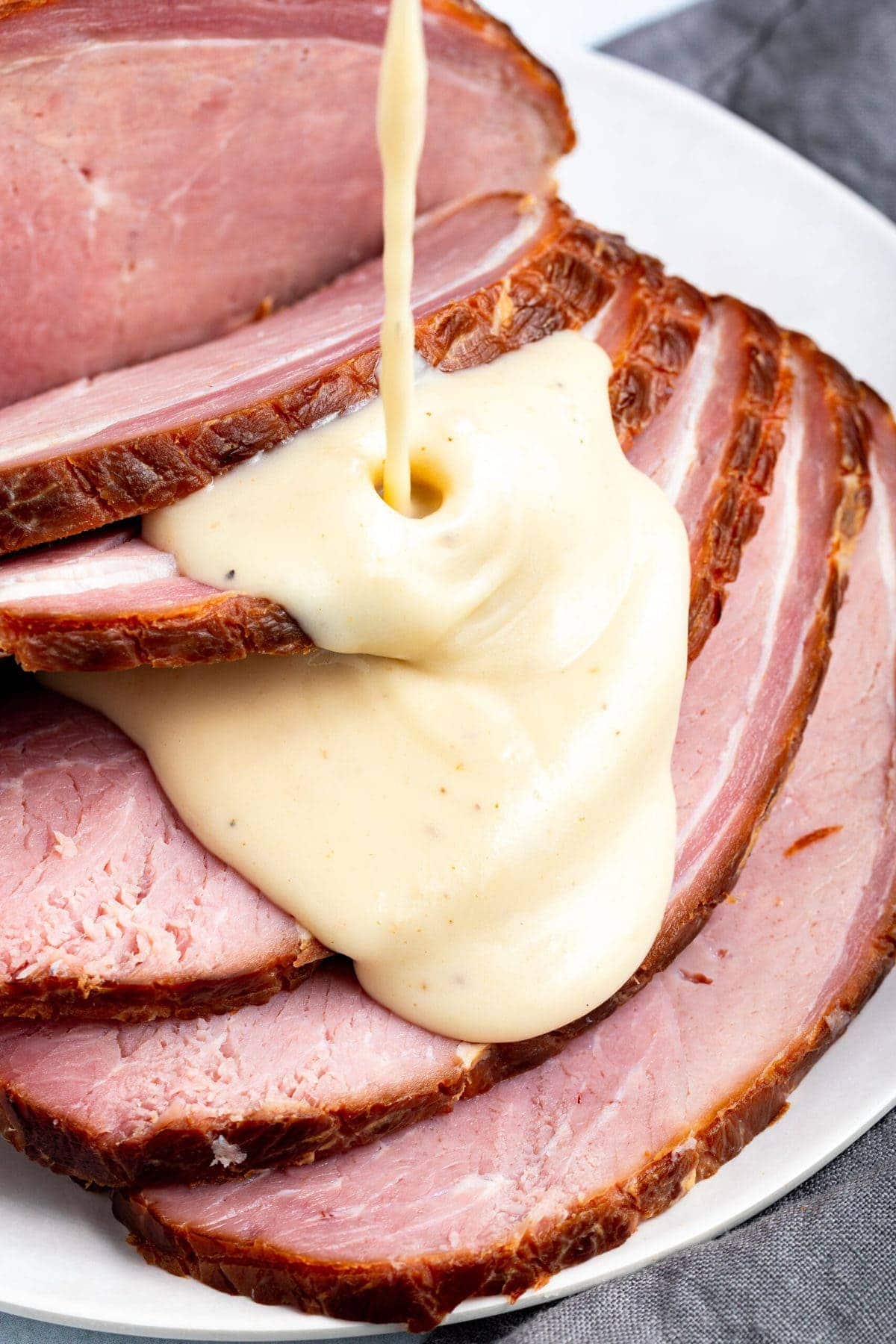 Sliced ham with ham gravy being poured over the top.