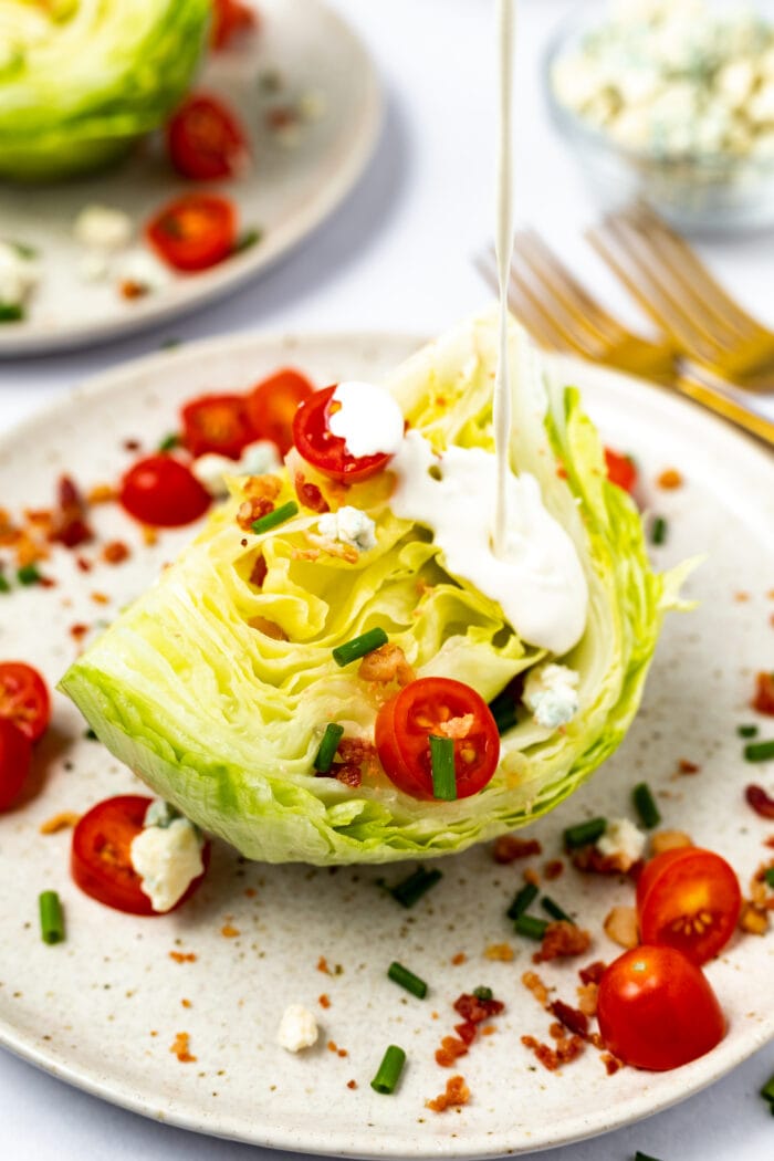 Roquefort dressing being poured over a wedge salad.