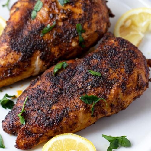 Blackened chicken on a white plate with lemon wedge garnish - easy chicken recipes for dinners with few ingredients