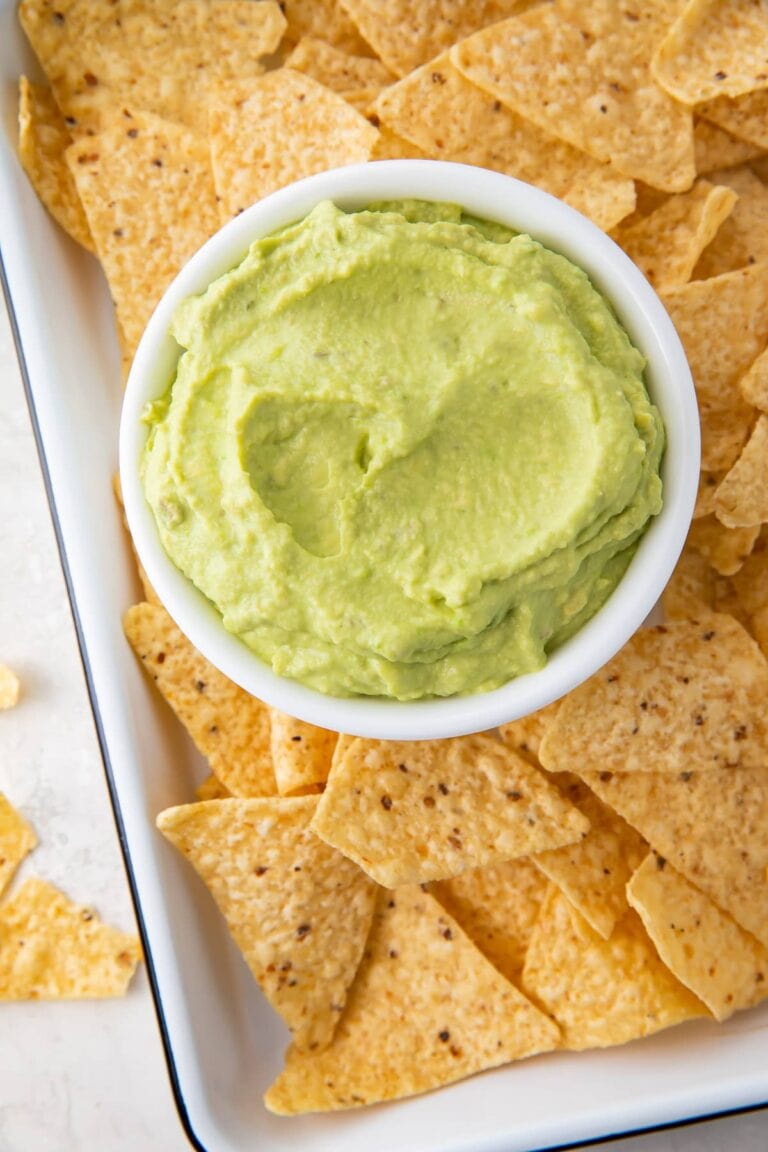 Guacamole dip in a bowl on a platter with tortilla chips