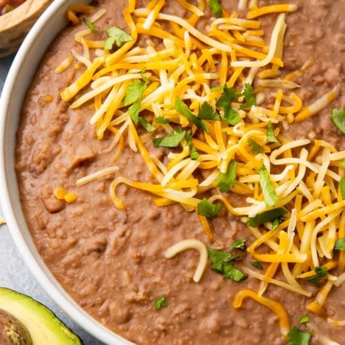 Instant Pot refried beans in a bowl topped with shredded cheese