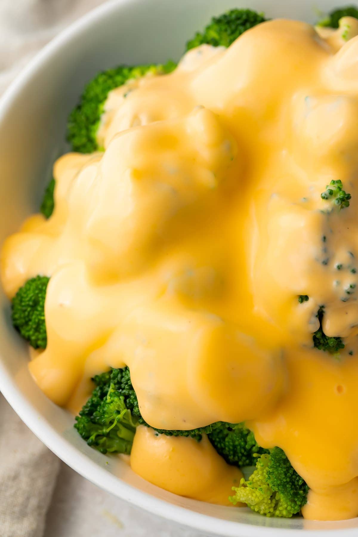 Keto cheese sauce smothering a bowl of broccoli florets