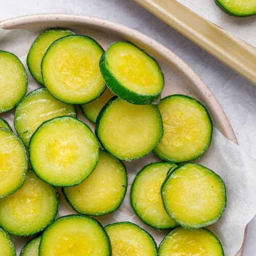 frozen sliced zucchini on a plate and on a baking tray