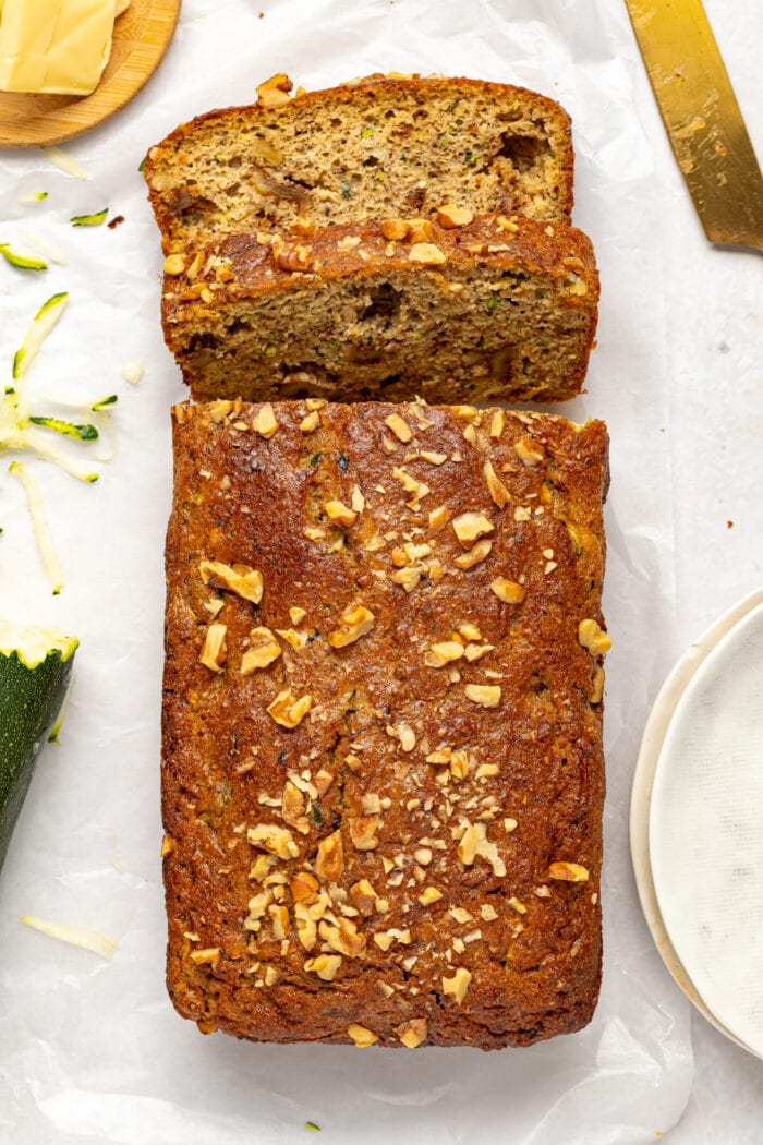 overhead image of keto zucchini bread surrounded by butter, shredded zucchini and a knife