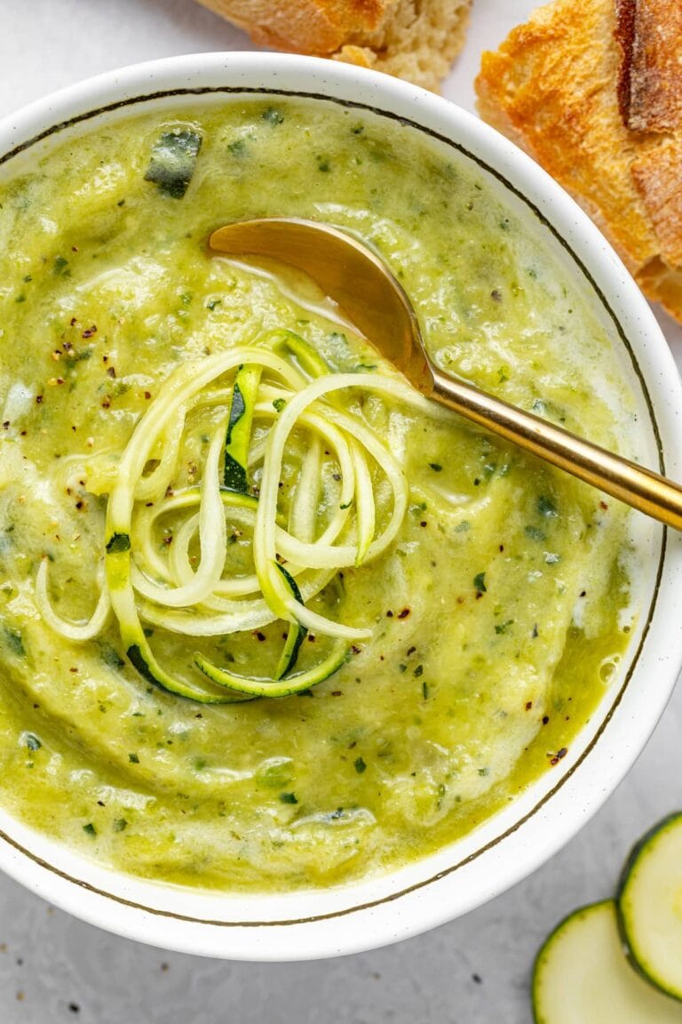 close up image of creamy zucchini soup with spiralized zucchini on top