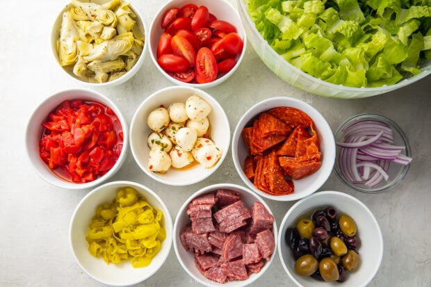 Ingredients for antipasto salad separated into small white bowls