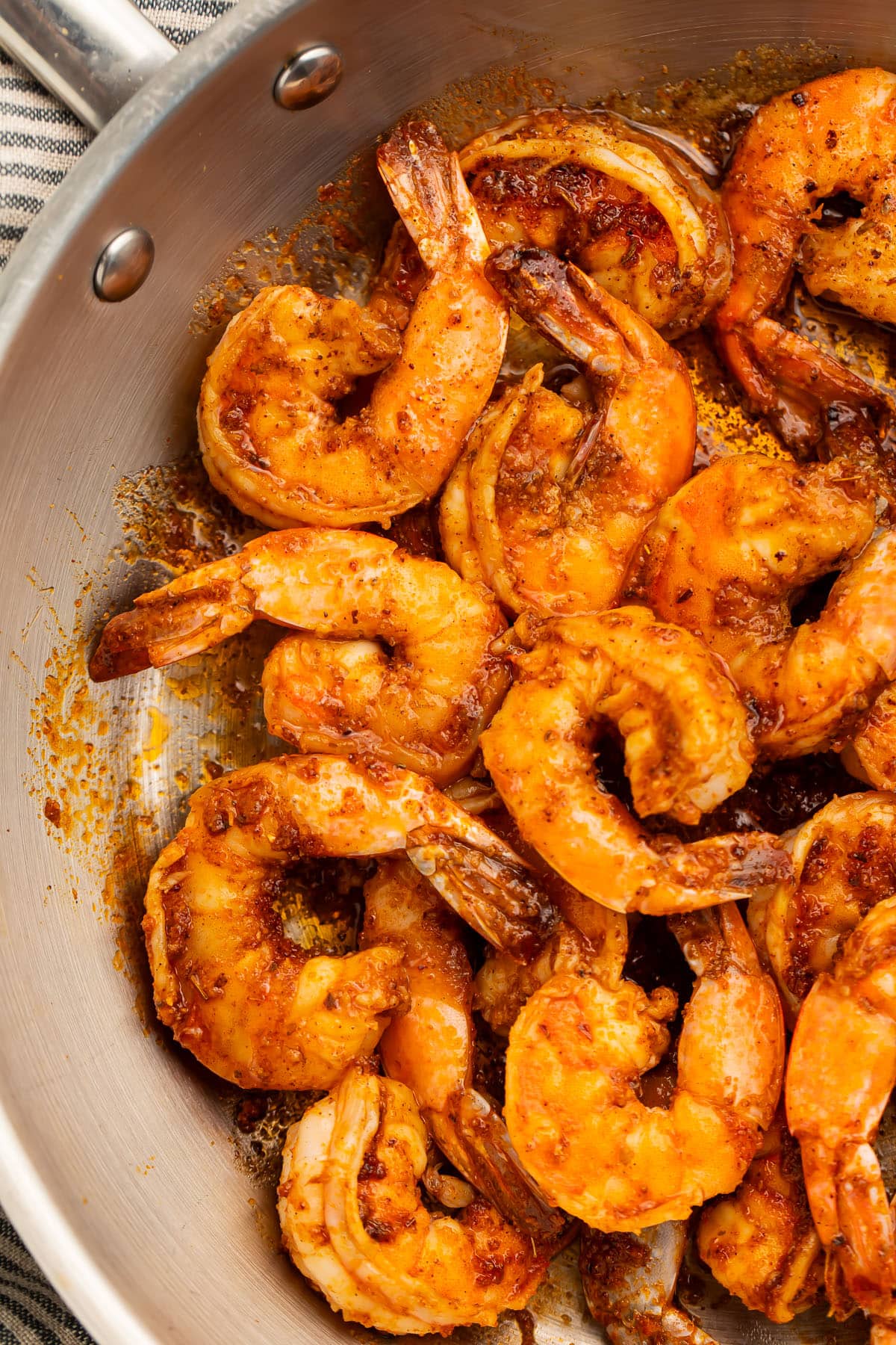 Close-up of tender, juicy Cajun shrimp in a large silver skillet.