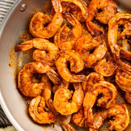 Close-up of tender, juicy Cajun shrimp in a large silver skillet.