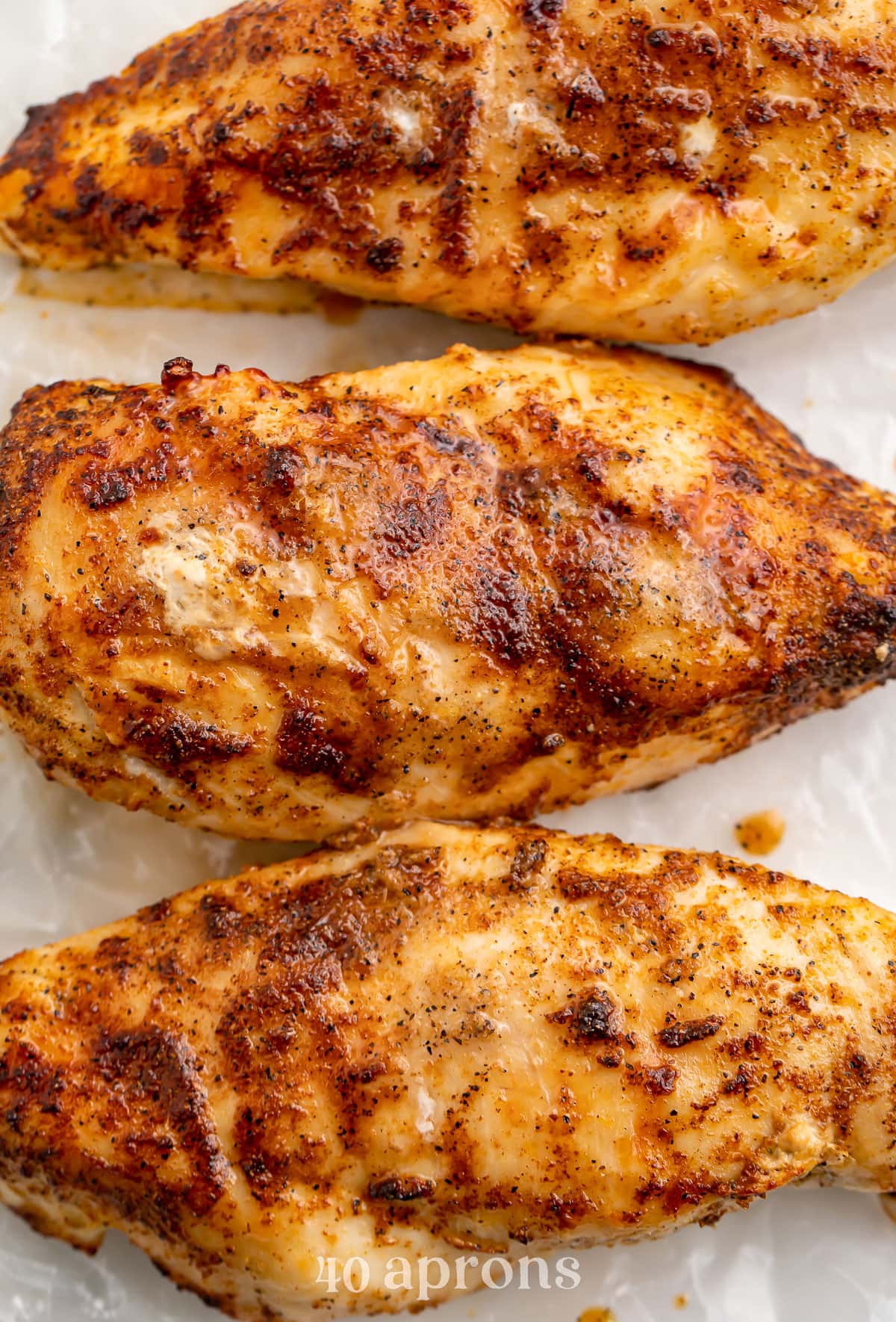 Three previously-frozen chicken breasts cooked in the air fryer then placed side-by-side on a plate.