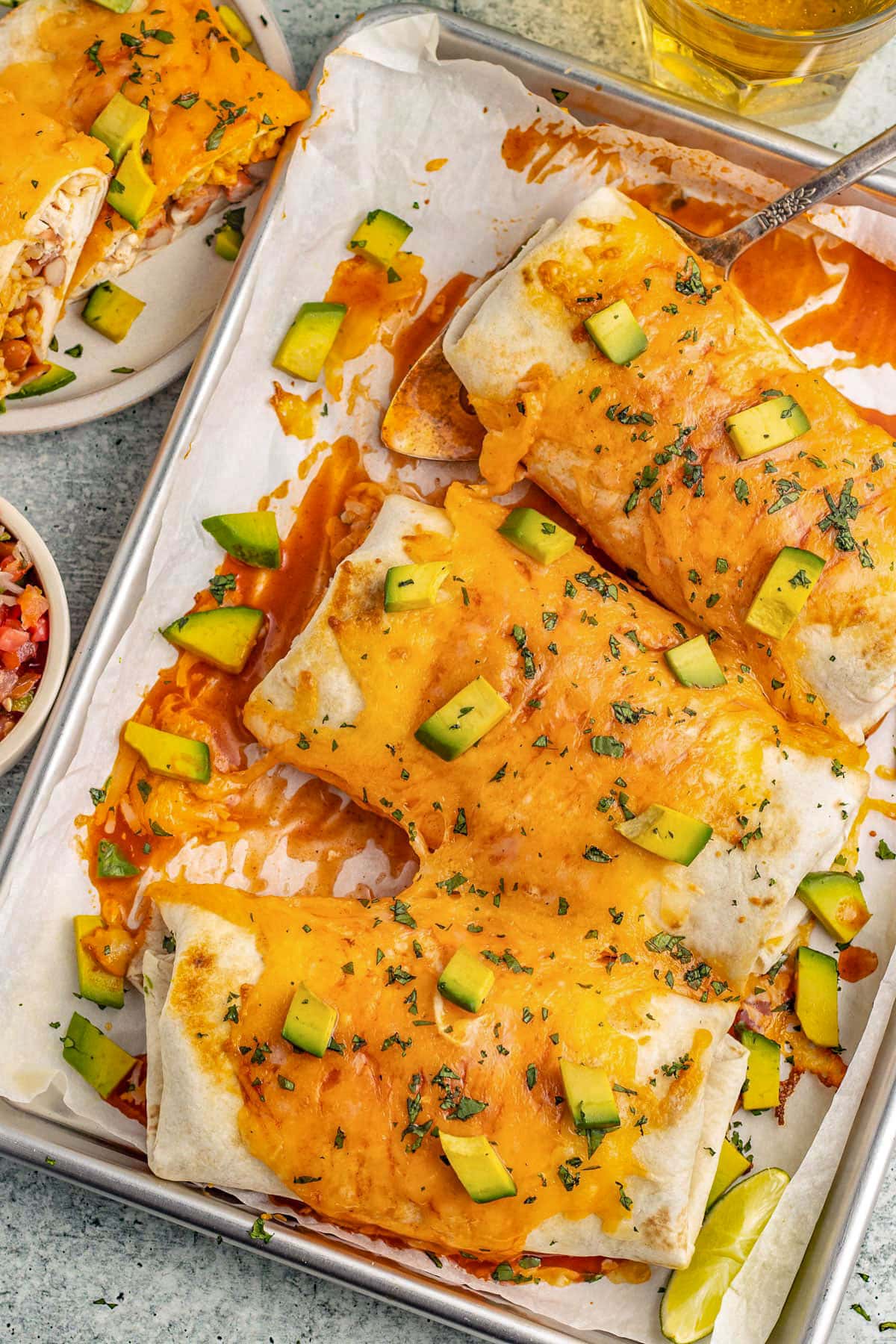 3 burritos suizos on a baking sheet lined with parchment paper.