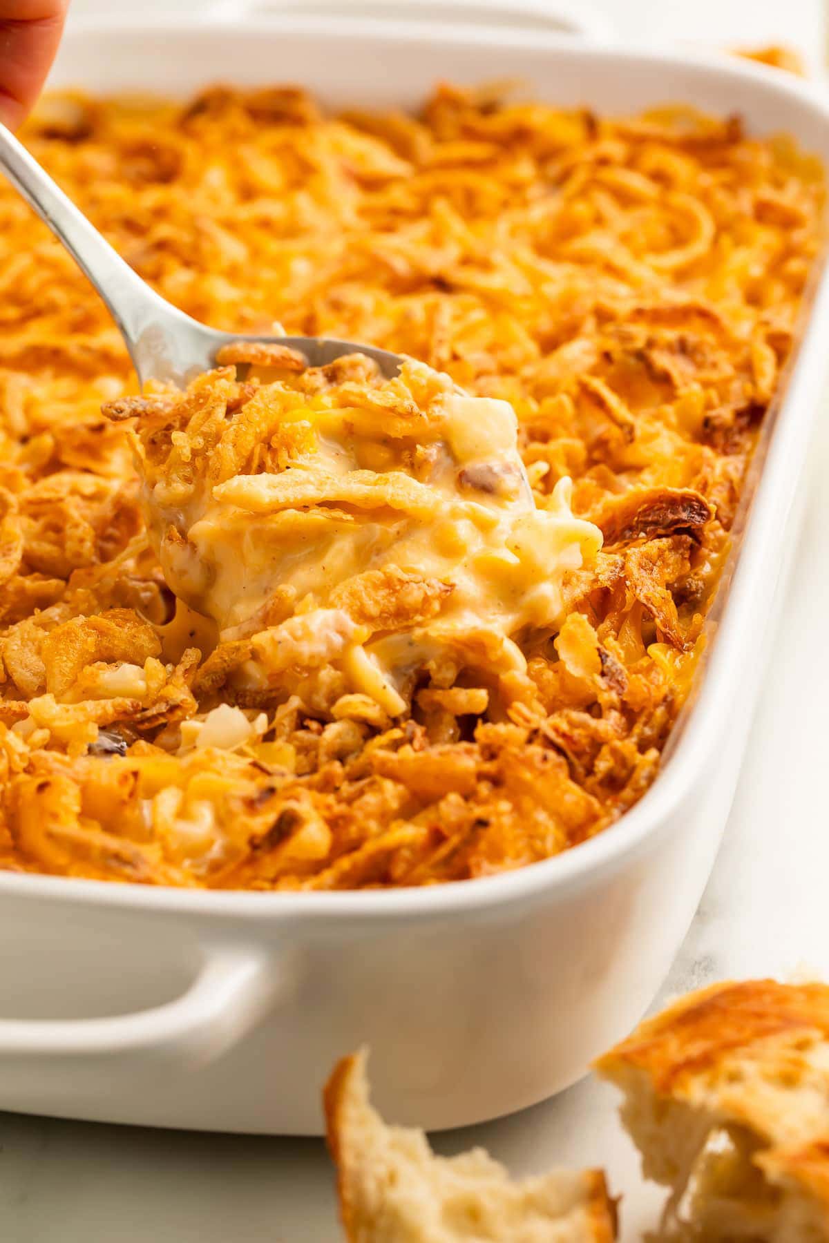 A spoonful of ultimate chicken casserole being lifted out of a casserole dish.