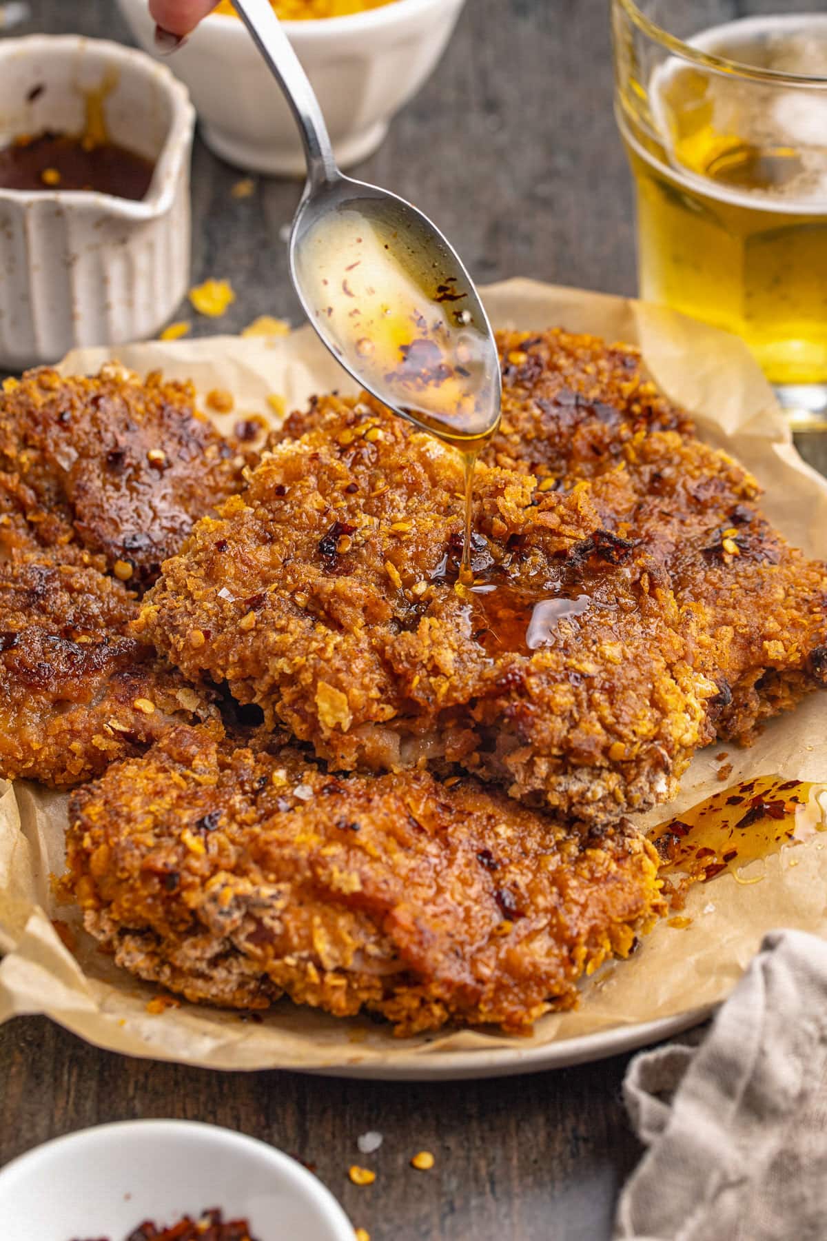 Crispy breaded hot honey chicken with hot honey being spooned on top of the chicken.