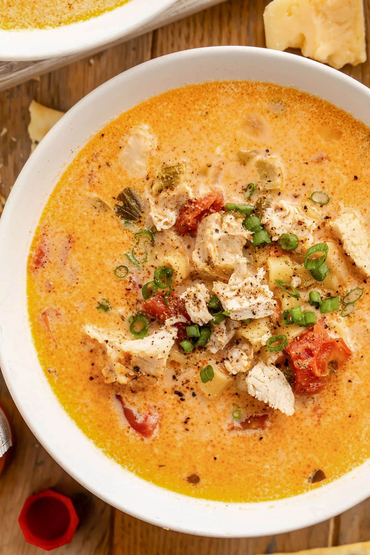 A bowl of cajun chicken pasta soup cooked in the Instant Pot on a dark wood table top.