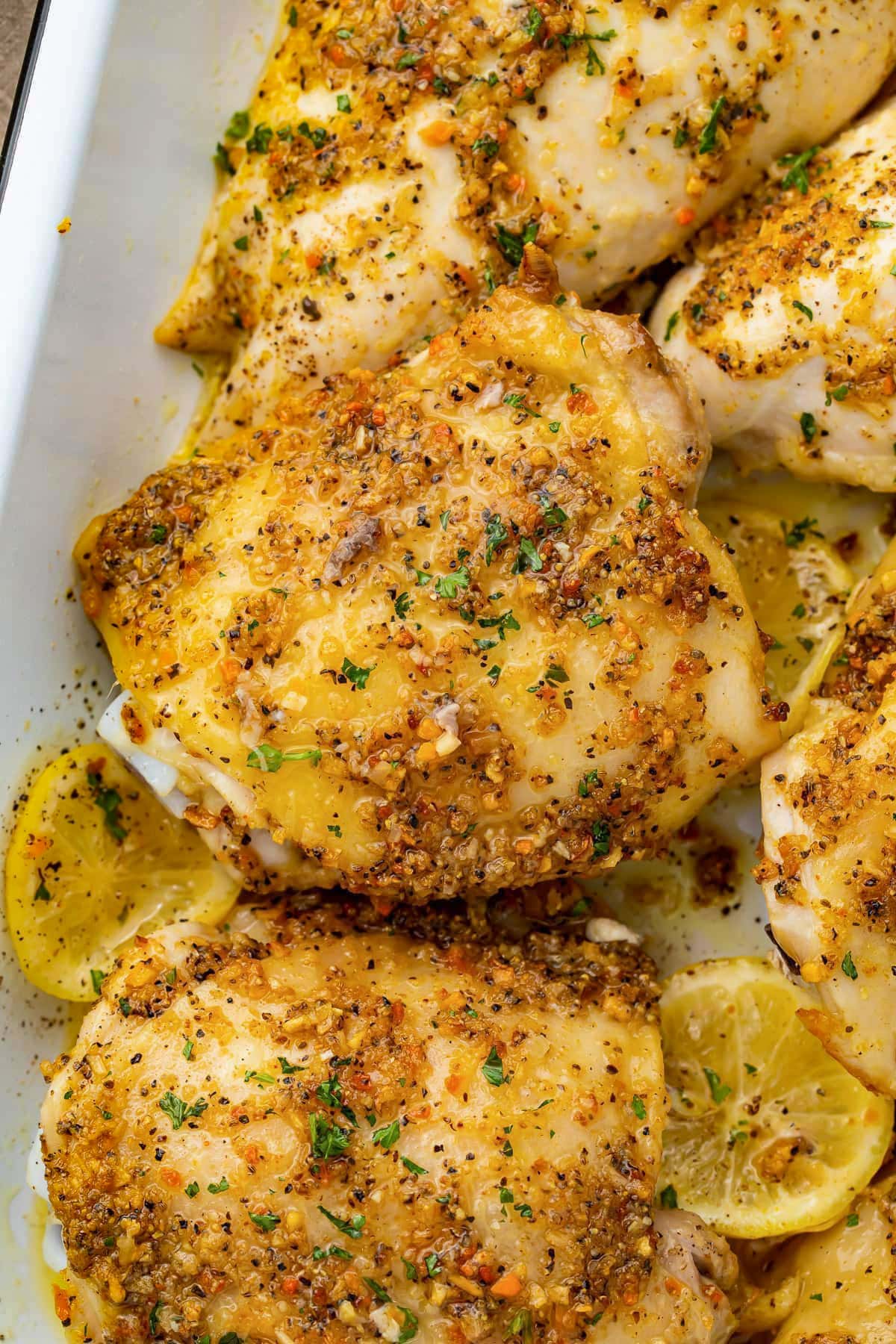 Lemon pepper seasoned chicken thighs in a casserole dish with lemon discs.