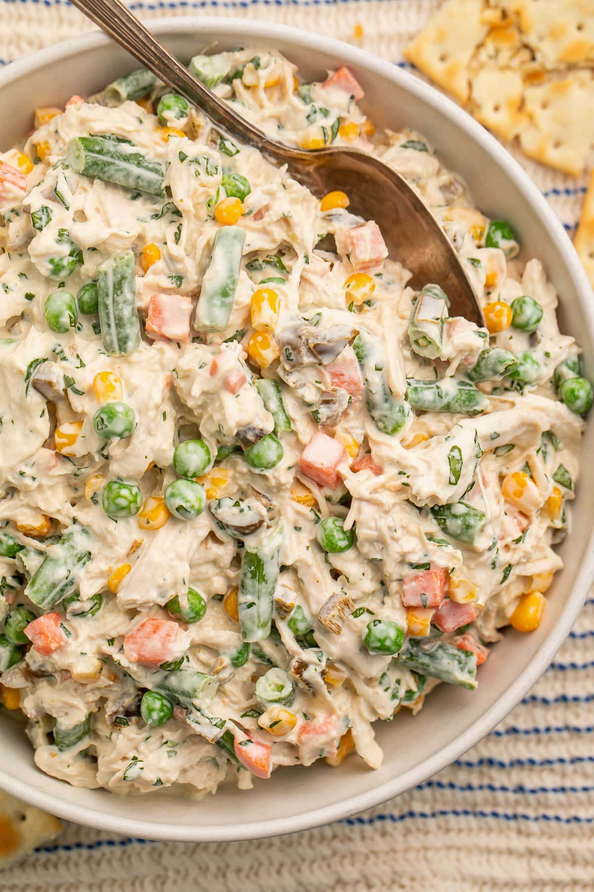 Top-down view of a large bowl of creamy Mexican chicken salad with fresh vegetables and a large silver spoon.