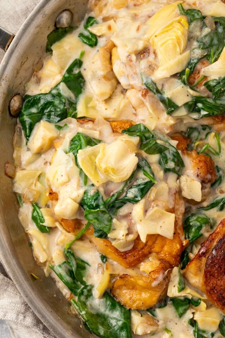 Close up photo of paleo spinach and artichoke chicken in a large silver pan