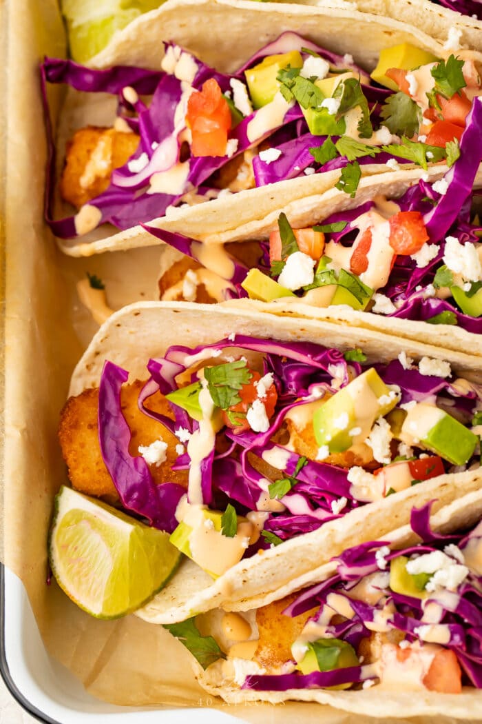 Close up view of fish stick tacos lined up in a baking dish