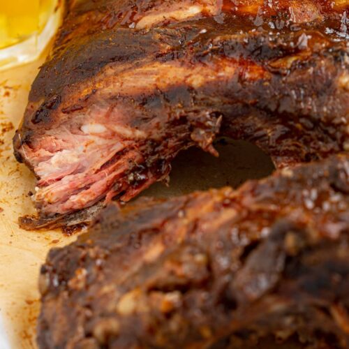 beef ribs on parchment paper with a glass of beer on the side