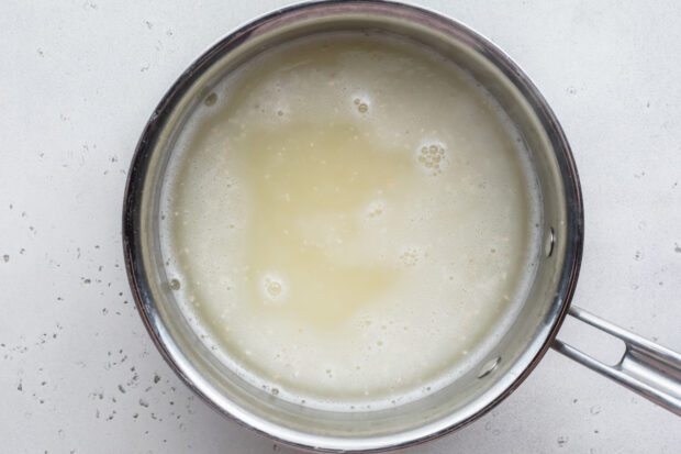 Overhead view of grits and water in large silver saucepan.