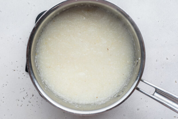 Overhead view of grits and water in large silver saucepan.