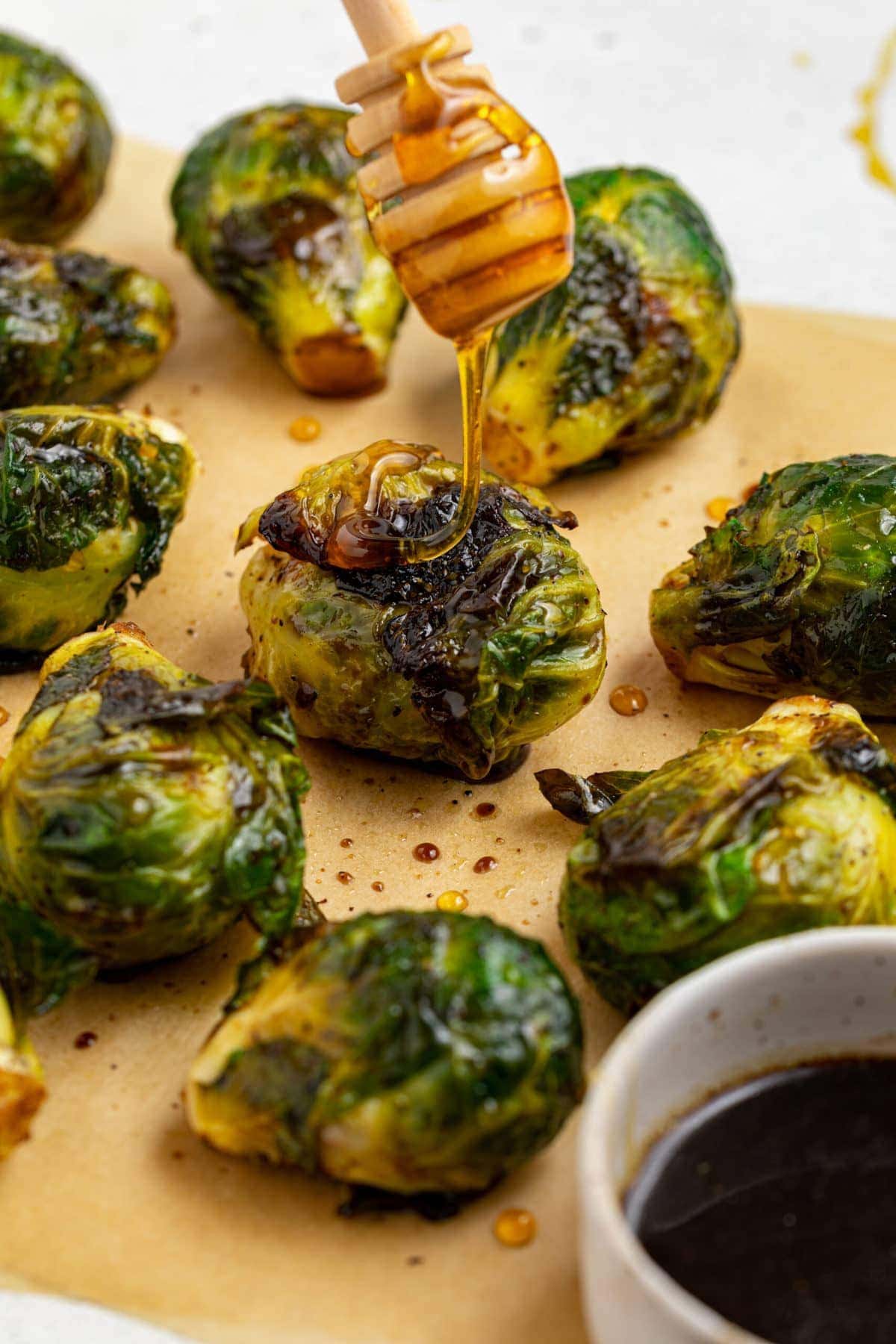 grilled brussels sprouts with honey being dripped over the top