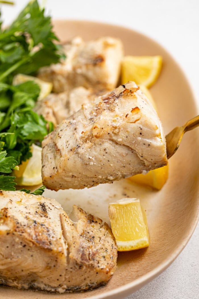 grilled mahi mahi fillet being lifted off of a serving platter