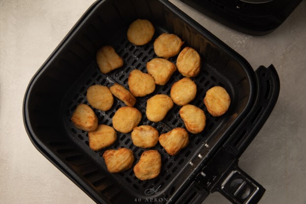 Frozen chicken nuggets in an air fryer basket