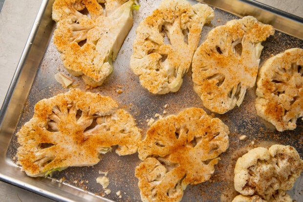 Seasoned cauliflower steaks on baking sheet