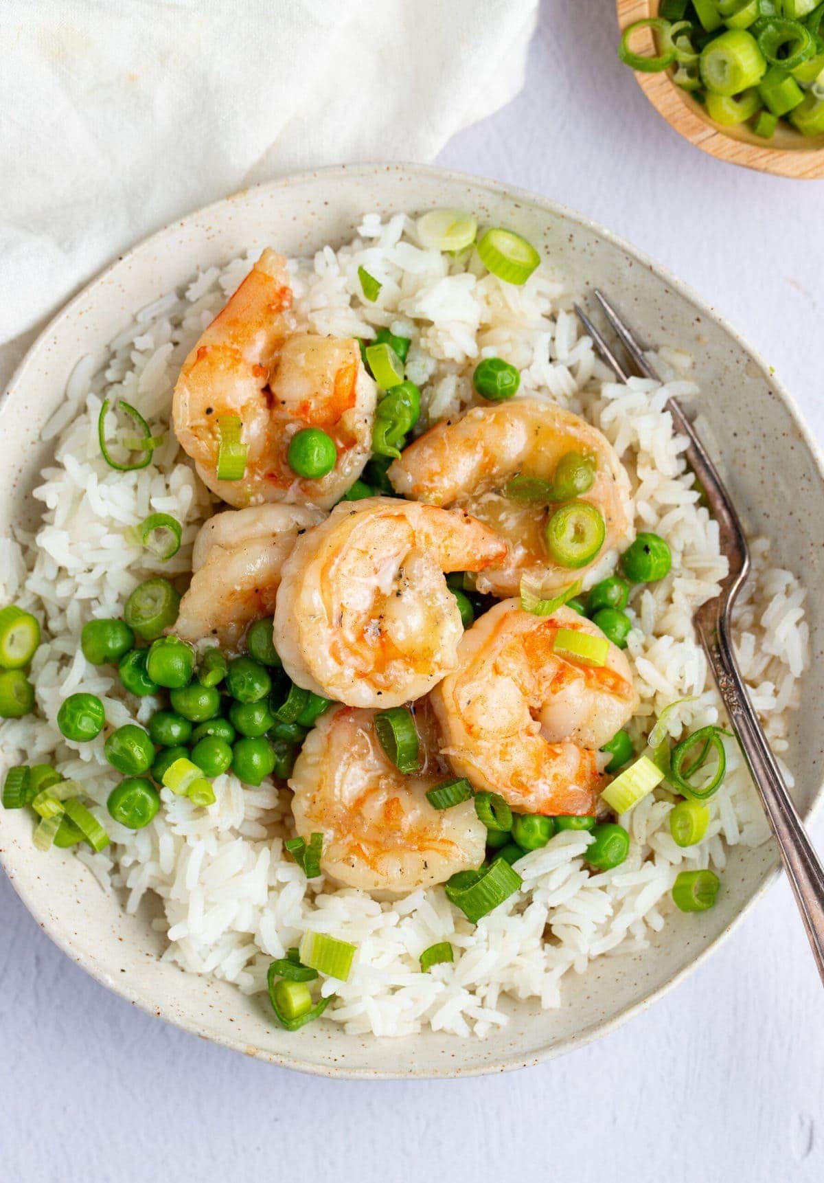 Shrimp with lobster sauce on a bed of rice in a white bowl with a fork