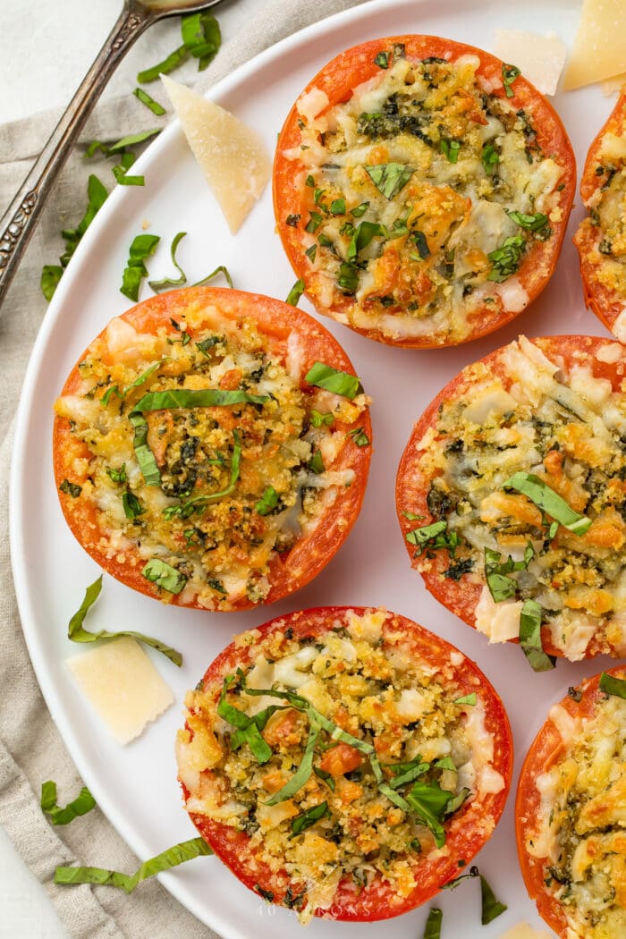 4 stuffed tomatoes on a plate with parmesan cheese