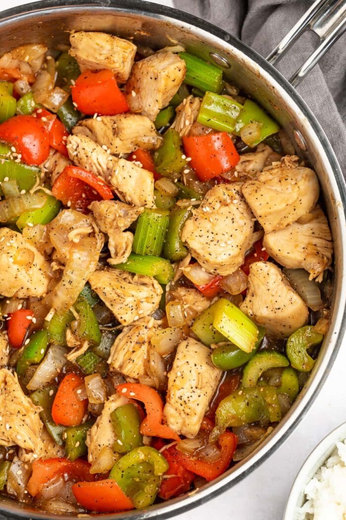 black pepper chicken in a skillet with rice on the side