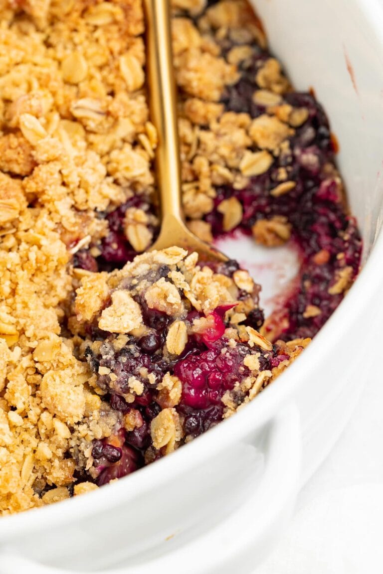 blackberry crumble being spooned out of a baking dish