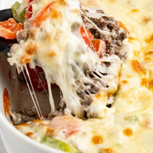 philly cheesesteak casserole being lifted out of the baking dish with a spatula