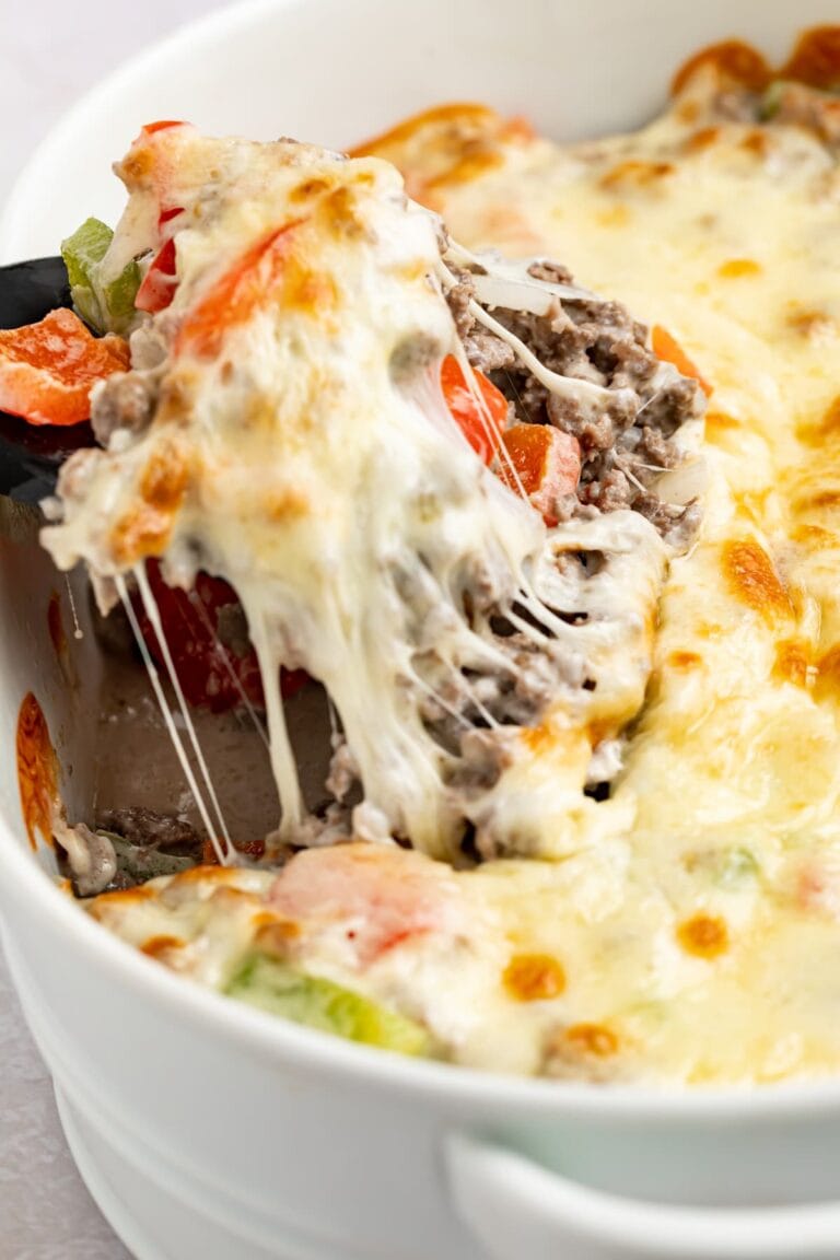 philly cheesesteak casserole being lifted out of the baking dish with a spatula