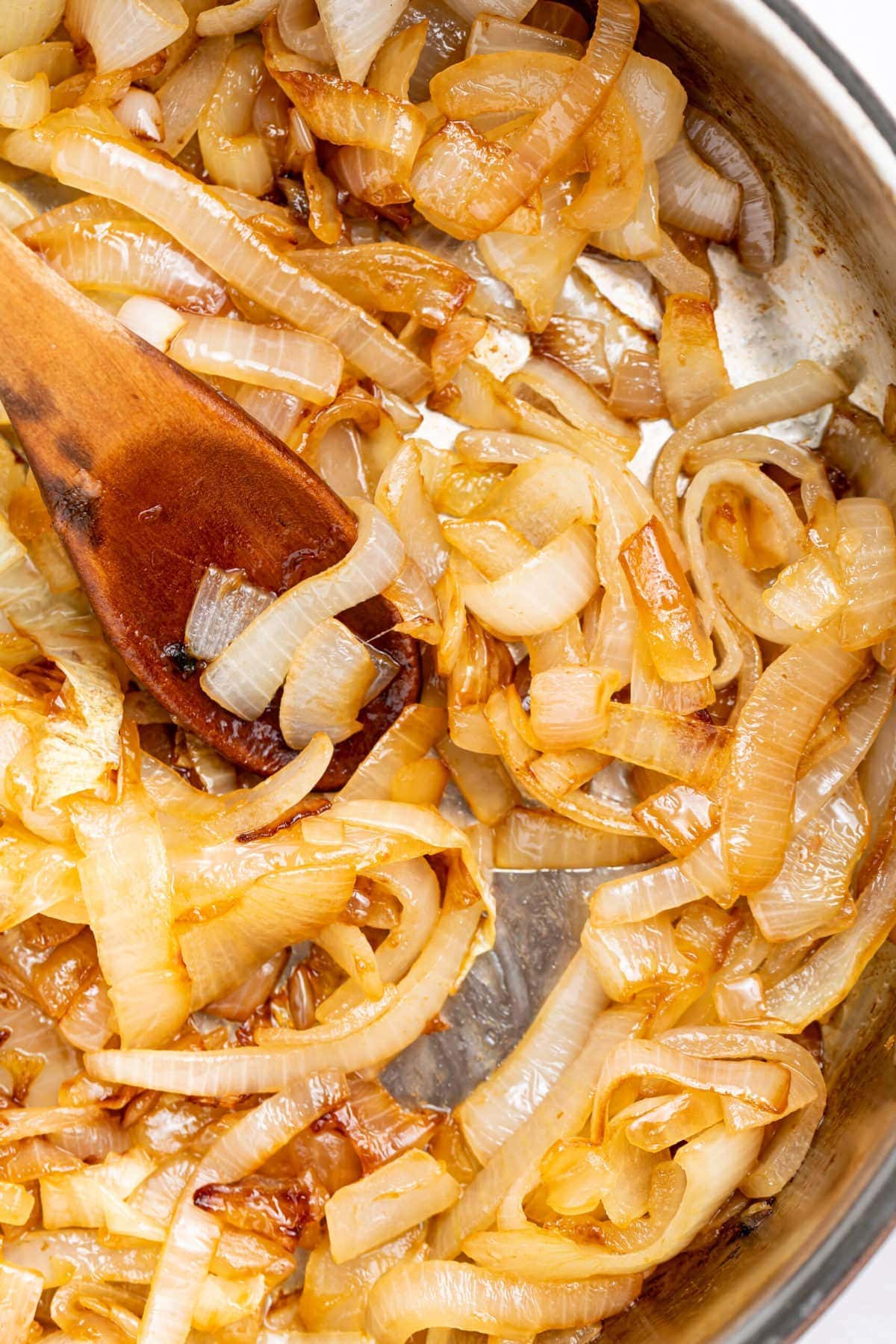 sauteed onions in a skillet with a wooden spoon