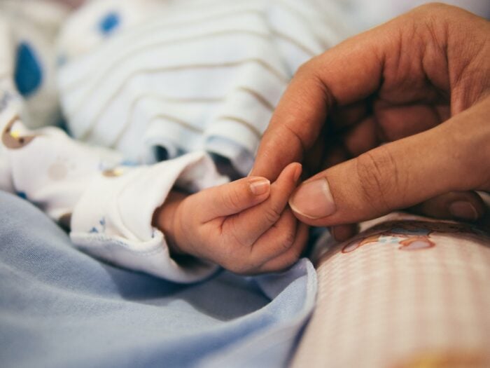 Woman holding baby's hand - natural birth with epidural