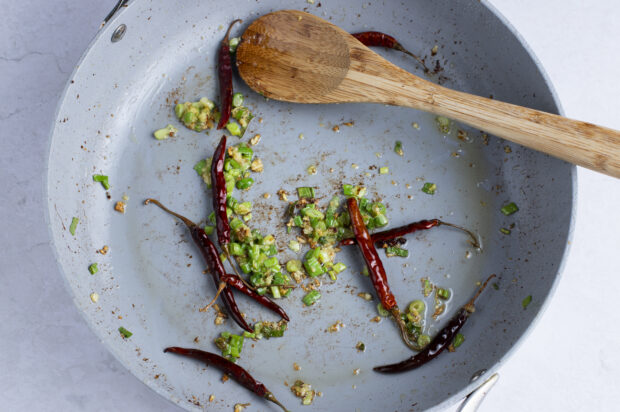 Aromatics for kung pao beef in large skillet with wooden spoon