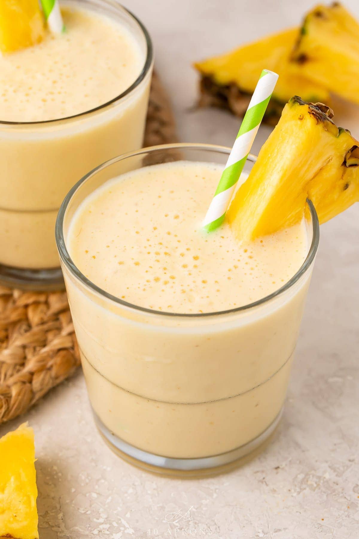 Short glasses of pineapple smoothie with a pineapple wedge garnish