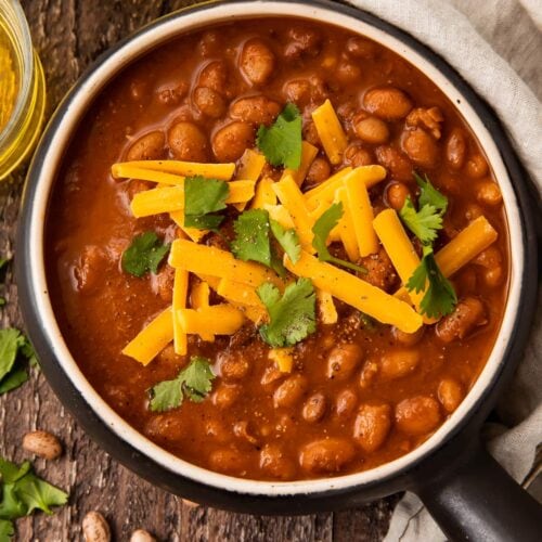 Overhead photo of ranch style beans in a black bowl on a wooden table