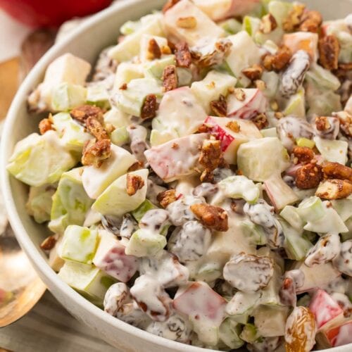 Slightly zoomed out shot of apple salad in a large bowl, with whole apples in the background