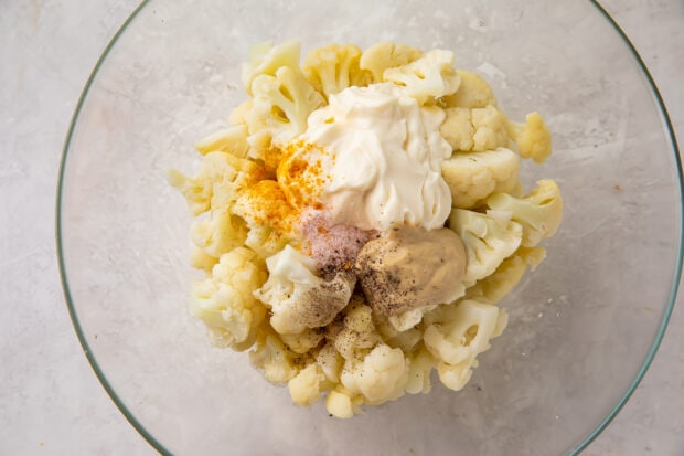 Cauliflower potato salad ingredients in a glass mixing bowl