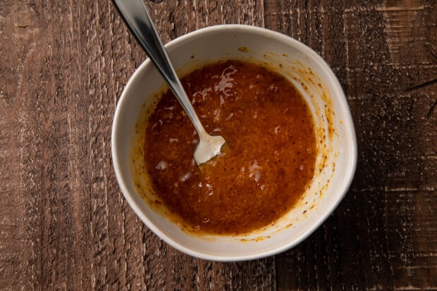 Orange-horseradish sauce in a small bowl with a spoon on a wooden table