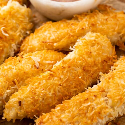 Crispy beer-battered coconut chicken on a plate next to orange-horseradish sauce