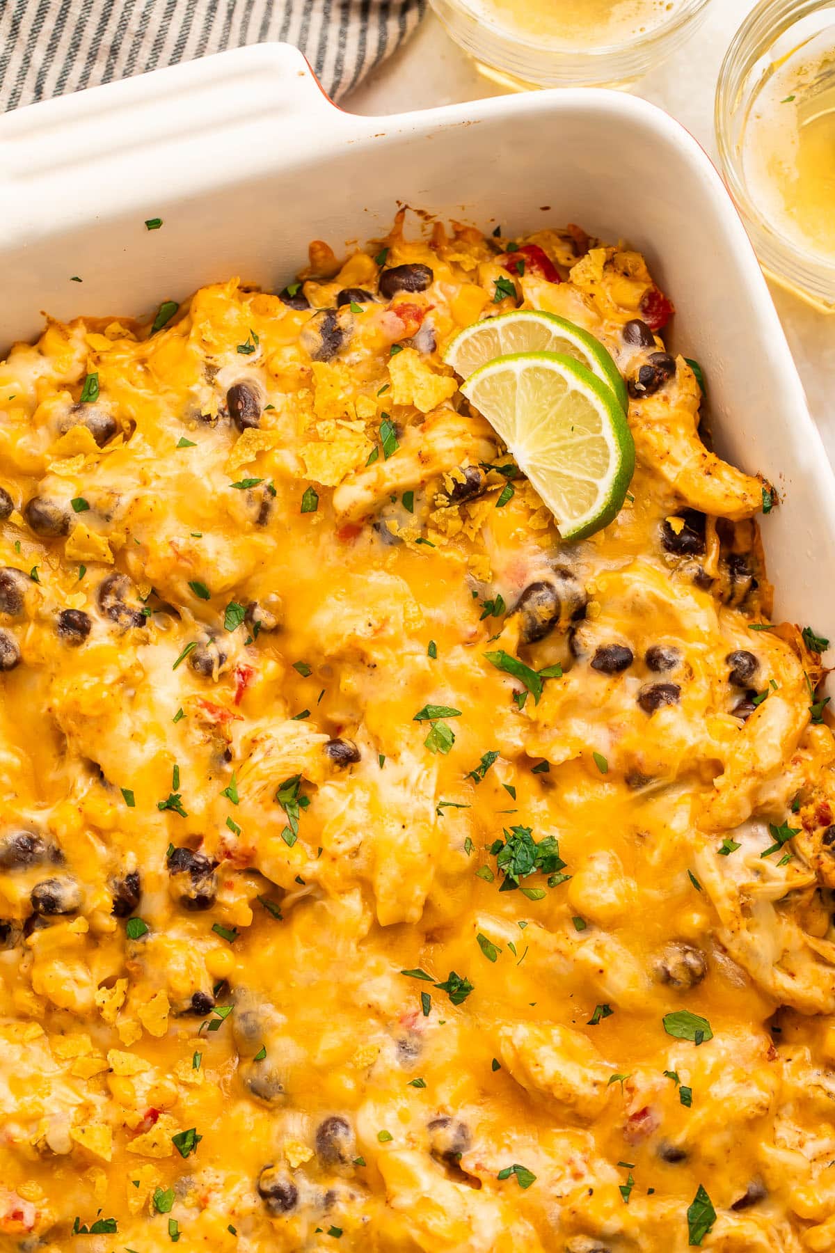 Overhead view of a casserole dish holding a Mexican chicken casserole topped with melted cheese and two lime wedges.