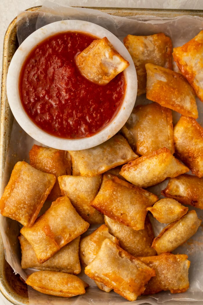 Pizza rolls cooked in the air fryer on a plate with a bowl of pizza sauce