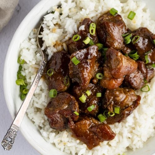 Pork adobo on top of white rice in a serving bowl