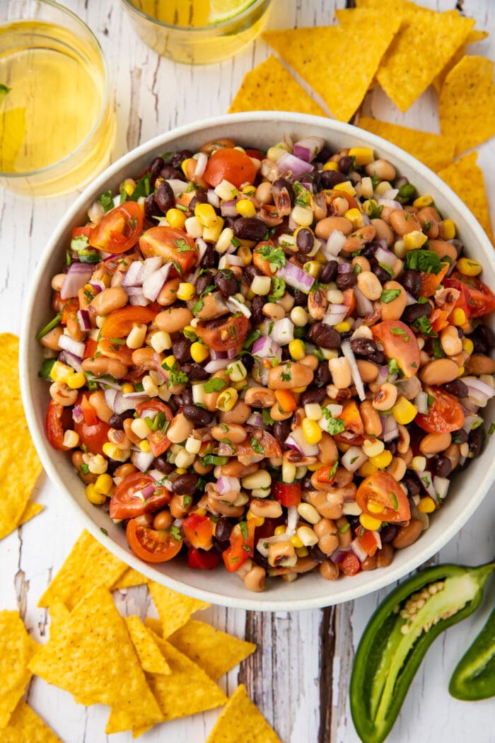 Overhead view of Texas caviar in a large bowl surrounded by chips and jalapenos