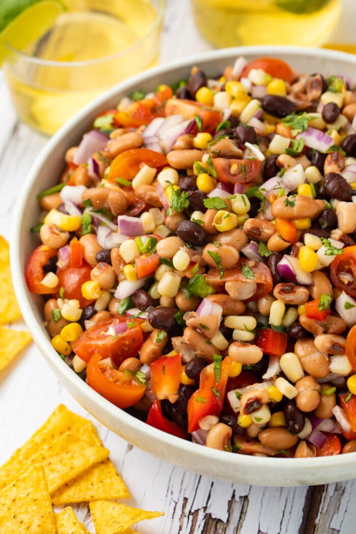 Texas caviar in a white bowl surrounded by chips